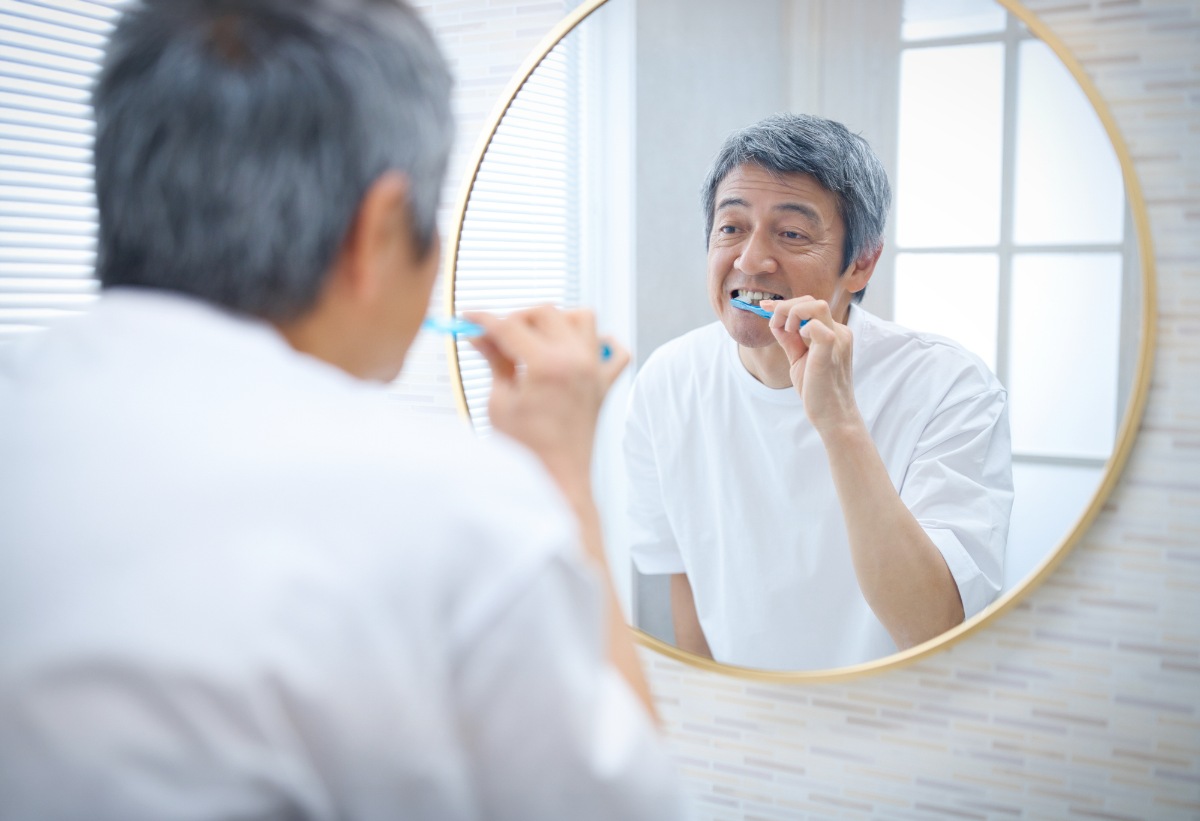 鏡を見ながらしっかり歯磨きをするミドル男性