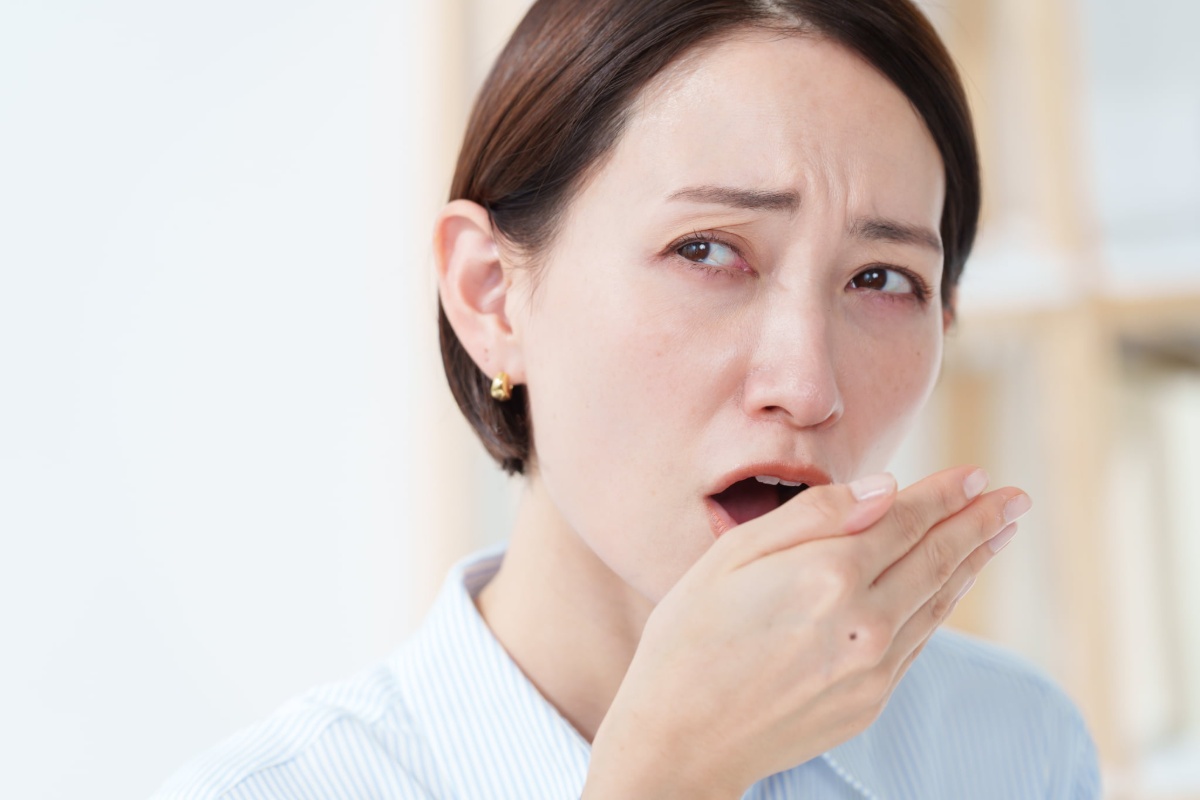 口臭を感じて手に息を吹きかけて臭いを確認する女性